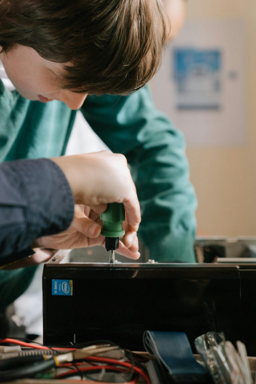 Close-up of hands repairing a computer with a screwdriver inside.